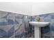 Powder room features a pedestal sink, brass fixtures, and stylish, geometric blue tiling at 4012 Old Sturbridge Dr, Apex, NC 27539