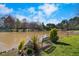 Picturesque waterfront view featuring manicured lawn, mature shrubbery, and peaceful pond at 406 Southshore Pkwy, Durham, NC 27703