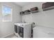 Well-organized laundry room with modern washer and dryer, storage shelves, and a window for natural light at 428 Beaverdam Lake Dr, Fuquay Varina, NC 27526