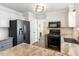 Bright kitchen featuring white and gray cabinets, granite countertops, and black appliances at 4725 Sinclair Dr, Raleigh, NC 27616