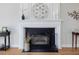Close-up of a fireplace with a white mantel decorated with modern art and candles, set against hardwood floors at 4818 Glendarion Dr, Durham, NC 27713