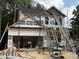 New two-story home under construction with black roof, ladders, open garage, and partially-installed siding at 49 Fetterbush Way, Clayton, NC 27520