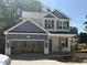 New two-story home featuring a two-car garage, light gray siding, black shutters and a brick foundation in a suburban neighborhood at 49 Fetterbush Way, Clayton, NC 27520