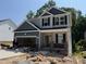 Charming two-story home featuring a brick porch, open garage, and light gray and navy blue siding at 49 Fetterbush Way, Clayton, NC 27520