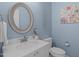 Stylish powder room featuring modern vanity, elegant mirror, and soft blue walls, perfect for guests at 5220 Linksland Dr, Holly Springs, NC 27540