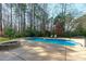 Beautiful in-ground pool with a stone fire pit and lounge chairs at 5220 Linksland Dr, Holly Springs, NC 27540