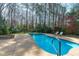 Beautiful in-ground pool with a stone fire pit and lounge chairs at 5220 Linksland Dr, Holly Springs, NC 27540