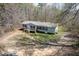 An aerial view of the single-level house with a front porch surrounded by a lush tree line and natural landscape at 55 J B Rd, Louisburg, NC 27549