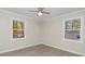 A bedroom with wood-look flooring, neutral walls, bright windows, and a modern ceiling fan at 5917 Meadowlark Ln, Raleigh, NC 27610