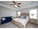 Bright main bedroom features a ceiling fan, tray ceiling, and a cozy sitting area with a blue velvet sofa at 5918 Giddings St, Raleigh, NC 27616