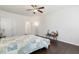 A bright bedroom with dark floors, ceiling fan, two doors, a small table with decor and a bed at 6021 Watsonia Dr, Zebulon, NC 27597