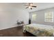 Bedroom with dark wood floors, ceiling fan, two windows, and a small table with decor at 6021 Watsonia Dr, Zebulon, NC 27597
