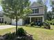 Two-story home featuring a two-car garage, manicured lawn, stone accents, and lush landscaping at 6021 Watsonia Dr, Zebulon, NC 27597