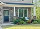 Inviting front porch with a charming door, decorative stone, and beautifully landscaped garden at 6021 Watsonia Dr, Zebulon, NC 27597