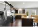 A modern kitchen with stainless appliances, granite countertops, a breakfast bar, and dark wood cabinets at 6021 Watsonia Dr, Zebulon, NC 27597