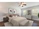 Comfortable main bedroom features two bedside windows, art, and a ceiling fan at 6021 Watsonia Dr, Zebulon, NC 27597