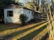 Exterior view of a white mobile home surrounded by trees and covered in dappled sunlight at 640 Crocker Rd, Smithfield, NC 27577
