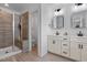 Modern bathroom featuring double vanity sinks, a glass-enclosed shower, and tiled floors at 6412 Nurture Ave, Raleigh, NC 27616