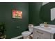 Elegant powder room with green walls, unique artwork, a vessel sink and designer fixtures at 6412 Nurture Ave, Raleigh, NC 27616