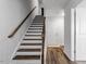 Staircase featuring wood treads, white risers, dark wood railing, and wood-look floors in the entryway at 6412 Nurture Ave, Raleigh, NC 27616