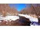 Serene view of a small snow-dusted creek flowing through the property's wooded landscape at 6509A Fowler Rd, Zebulon, NC 27597