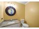 A quaint bathroom featuring granite countertops, a decorative mirror, neutral wall paint, and a white toilet at 7109 River Birch Dr, Raleigh, NC 27613