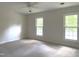 A bright bedroom featuring a ceiling fan, neutral walls, light-colored carpet, and two large windows at 7109 River Birch Dr, Raleigh, NC 27613