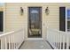 Close-up of the front door with decorative sidelights and a storm door, framed by a white railing at 7109 River Birch Dr, Raleigh, NC 27613