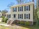 Classic two-story home with light yellow siding, black shutters, brick foundation, and landscaped front yard at 7109 River Birch Dr, Raleigh, NC 27613
