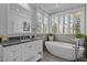 Bright bathroom features a soaking tub, grey countertop vanity, and large windows overlooking the yard at 73214 Burrington, Chapel Hill, NC 27517