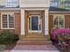 Close-up of the home's entrance boasting a navy door, brick steps, and vibrant pink azaleas in the landscaped front yard at 73214 Burrington, Chapel Hill, NC 27517