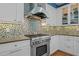 Gourmet kitchen featuring a stainless steel range, mosaic tile backsplash, and custom cabinetry at 73214 Burrington, Chapel Hill, NC 27517