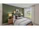 Comfortable bedroom showcasing a Queen bed, olive green accent wall, and bright natural light at 7750 Michelle Rd, Rocky Mount, NC 27803