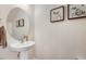 Well-lit half bathroom with a pedestal sink, round mirror, and decorative wall art at 825 Golden Plum Ln, Zebulon, NC 27597