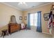 Bright bedroom with a dresser, ceiling fan, and a window with blue curtains at 8701 Neuse Village Ct, Raleigh, NC 27616