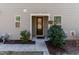 The front of this home features a covered entrance, windows, a well manicured lawn, and lush landscaping at 1012 Catch Fly Ln, Durham, NC 27713