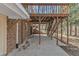 Open concrete patio area beneath a wooden deck with stairs leading to backyard and wooded area at 1133 Turner Farms Rd, Garner, NC 27529