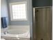 Bathroom featuring a soaking tub, a shower, and a window with privacy glass blocks at 126 W Quail Ridge Rd, Oxford, NC 27565