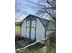 Backyard storage shed with double doors and a weathered appearance, surrounded by a chain link fence at 126 W Quail Ridge Rd, Oxford, NC 27565