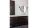 Bathroom vanity with dark wood cabinets, white countertop, round mirror, sconces and stylish fixtures at 186 Evington Dr, Pittsboro, NC 27312