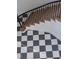 Elegant staircase featuring light wood steps, black metal railing, and classic black-and-white checkered flooring at 186 Evington Dr, Pittsboro, NC 27312