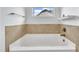 Bathroom featuring a bright tub with tiled accents, white walls and a small window at 208 Tarkenton Ct, Clayton, NC 27527