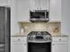 Close up on a gas range with stainless steel appliances, granite countertops and bright white cabinets at 208 Tarkenton Ct, Clayton, NC 27527