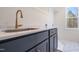 Laundry room sink with modern gold faucet, quartz countertop, blue-gray cabinets, and window view at 216 Meadow Walk Dr, Fuquay Varina, NC 27526