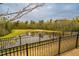 Scenic view of the community pond, surrounded by lush greenery and a secure fence at 237 Abercorn Cir, Chapel Hill, NC 27516