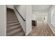 Carpeted staircase adjacent to an open-concept kitchen and living area with wood-look flooring at 248 Shingle Oak Rd, Wake Forest, NC 27587
