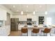 Well-lit kitchen features white cabinets, stainless steel appliances, a large island and hardwood floors at 249 Spilona Way # 64, Four Oaks, NC 27524