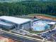 Aerial view of a modern YMCA facility with an outdoor pool, water slide, ample parking, and wooded surroundings at 249 Wendover Pkwy, Pittsboro, NC 27312
