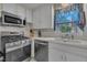 Modern stainless steel cooktop and oven, with white cabinets and window view to natural light at 3022 Dixon Rd, Durham, NC 27707