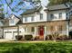 Charming two-story home featuring a welcoming front porch, landscaped yard, and bright red front door at 317 Flatrock Ln, Holly Springs, NC 27540